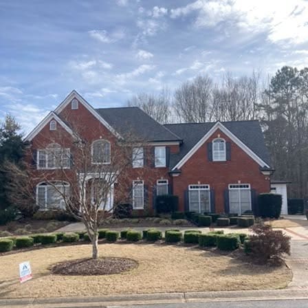 Two-story red brick suburban house with a front lawn and driveway