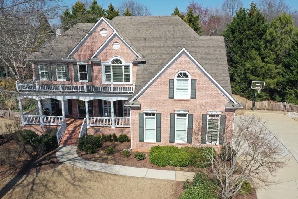 Large brick house with a wraparound porch and a basketball hoop in the driveway
